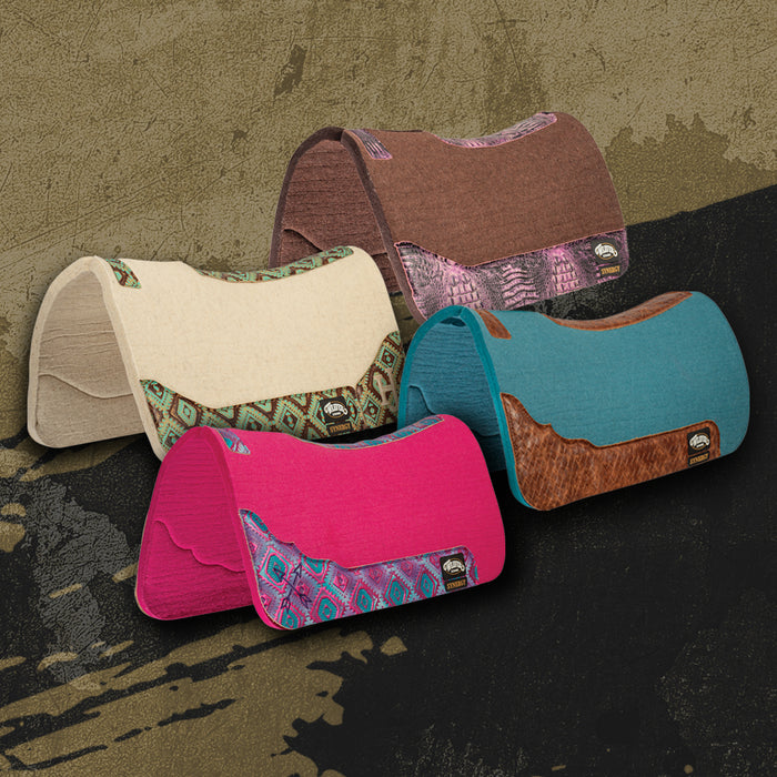 Collection of colorful custom saddle pads with leather and patterned fabric accents displayed on a rustic textured background.