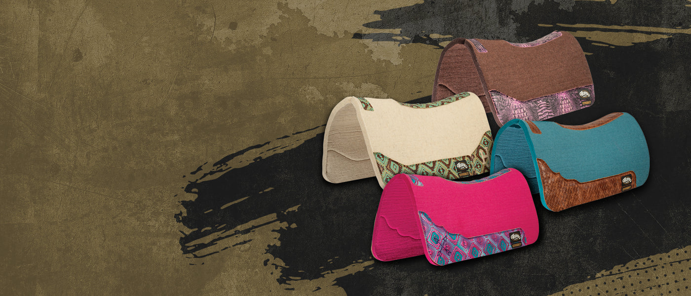 Collection of colorful custom saddle pads with leather and patterned fabric accents displayed on a rustic textured background.