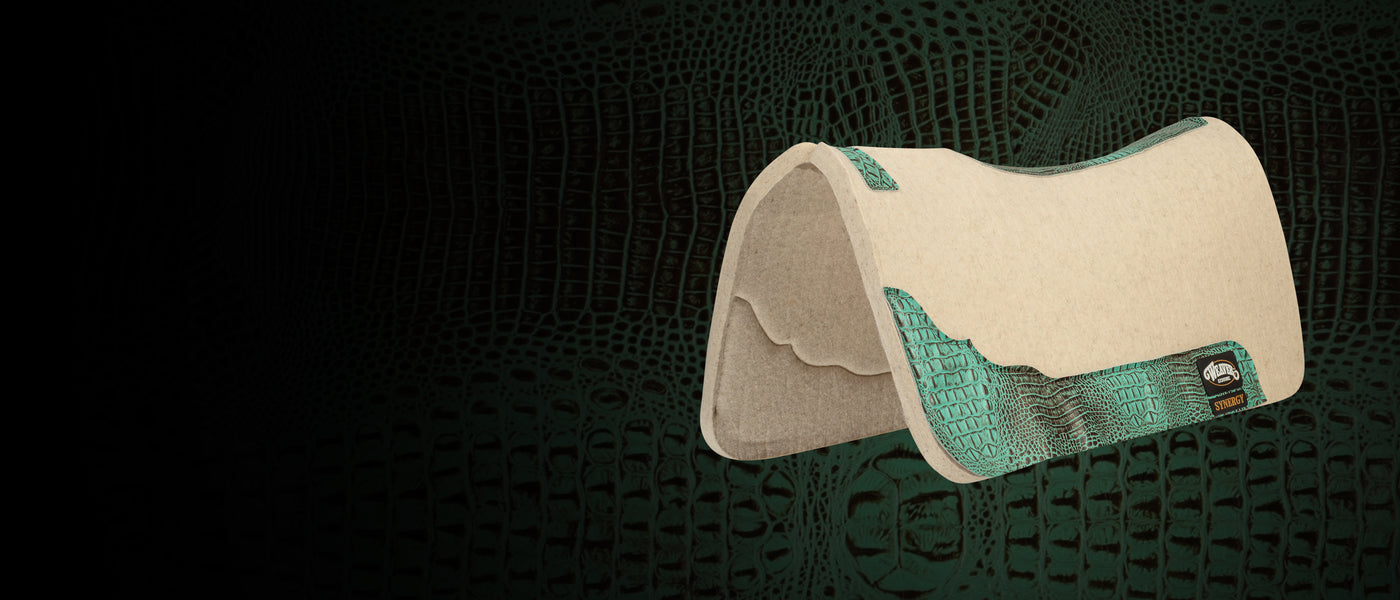 Natural felt saddle pad with turquoise croc-print leather wear leathers on a dark textured background